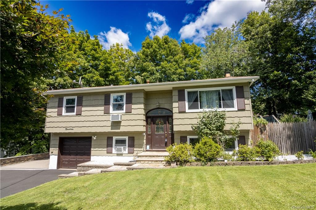 Split foyer home featuring a garage and a front yard