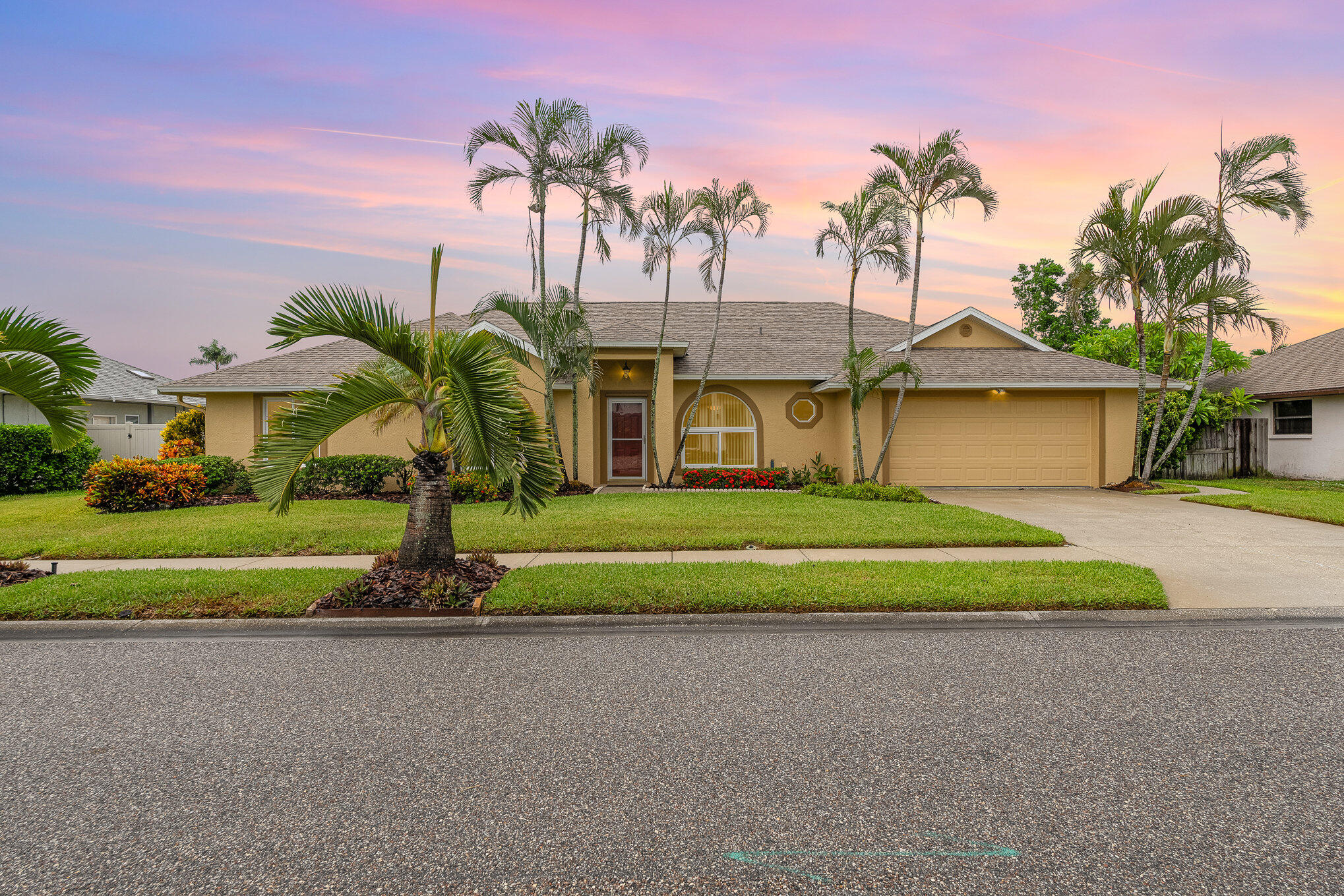 a front view of a house with a yard and palm trees