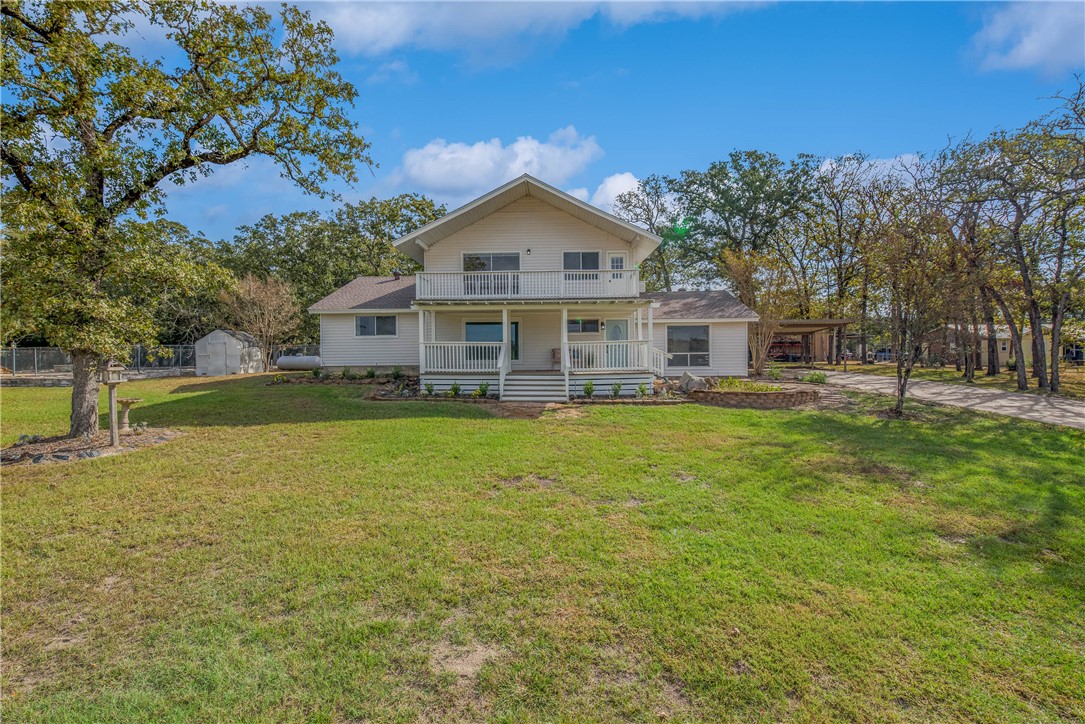 View of front of home with a balcony, a front yard