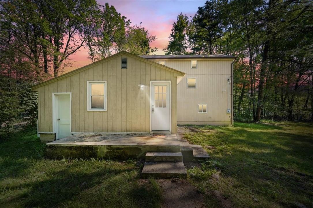 Back house at dusk with a yard and a patio area