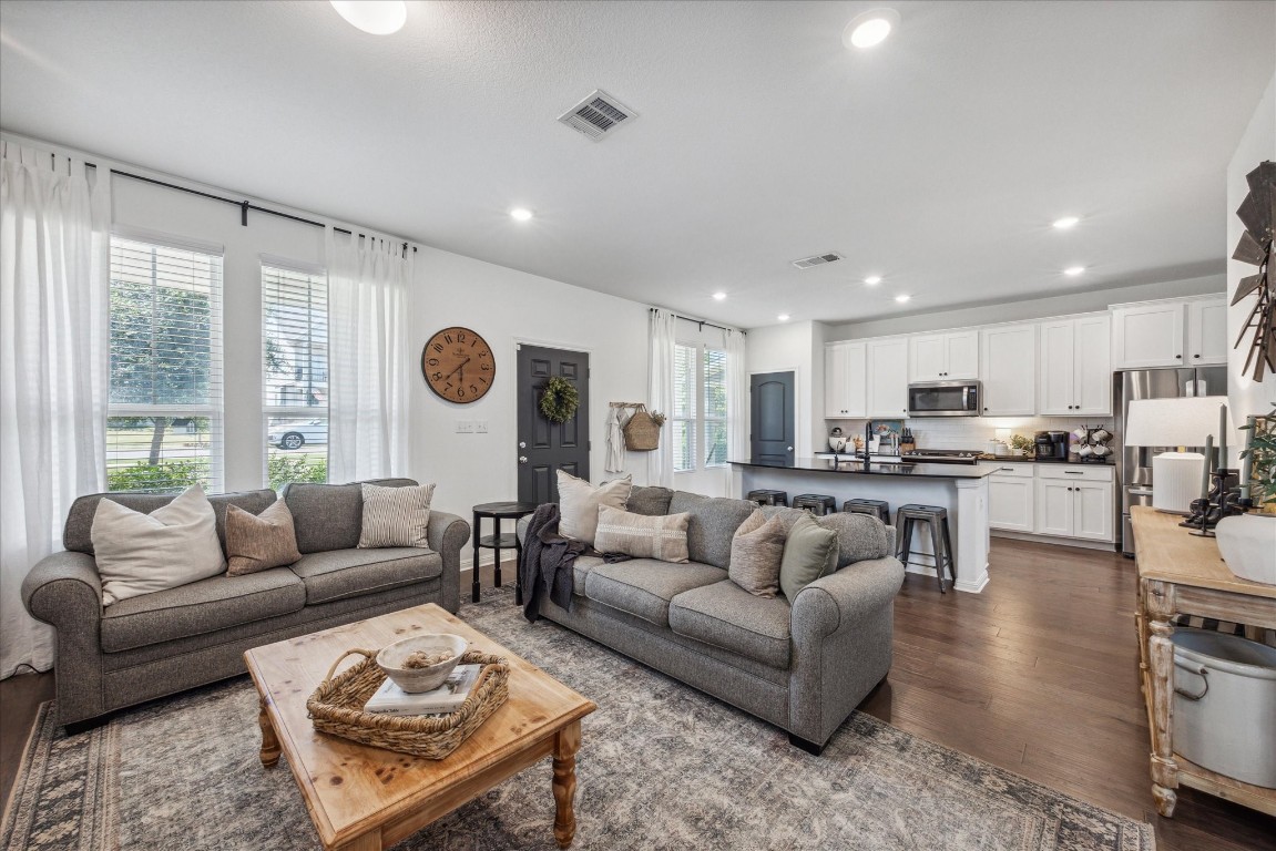 a living room with furniture kitchen view and a large window