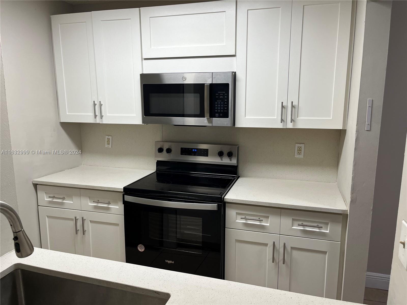 a kitchen with granite countertop white cabinets and stainless steel appliances