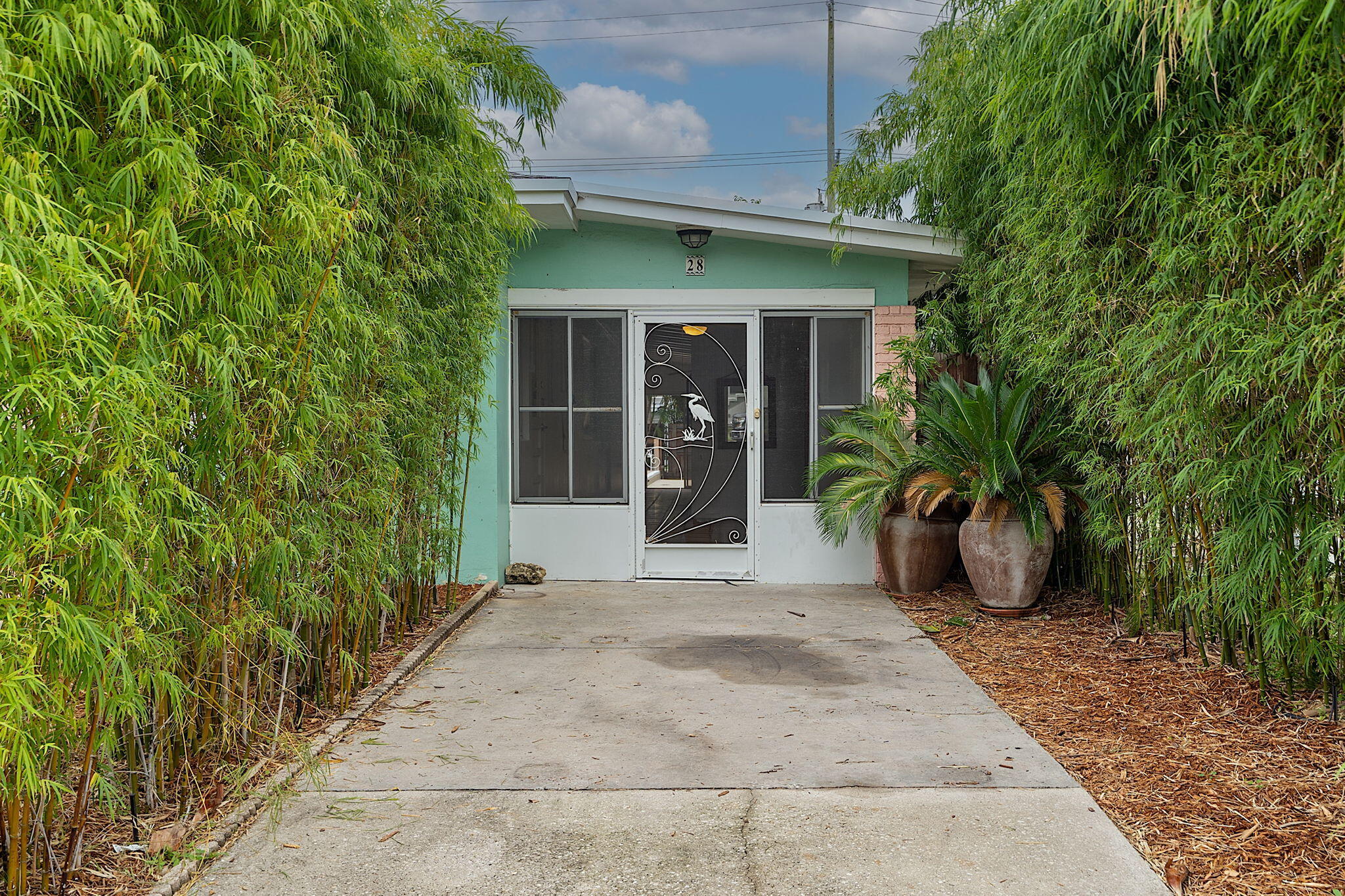 a view of a house with potted plants and a bench