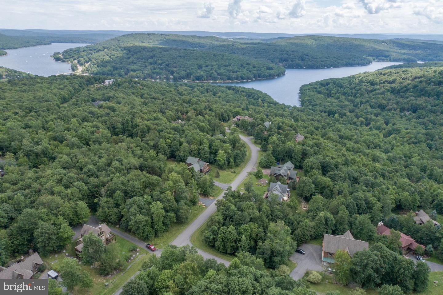 an aerial view of a houses with outdoor space and trees all around