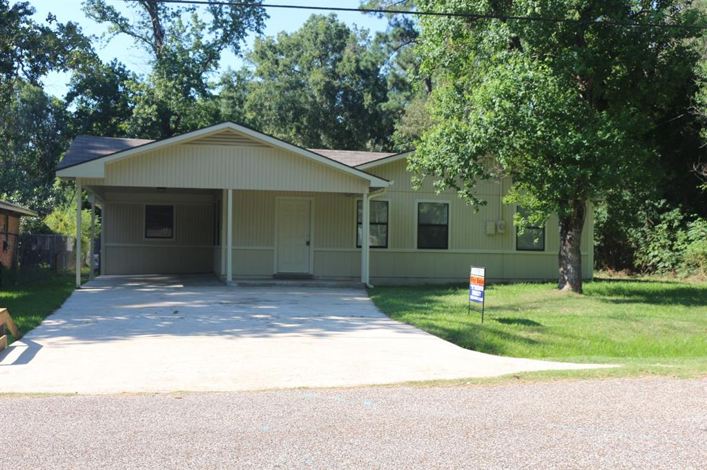 a view of a house with a yard plants and large tree