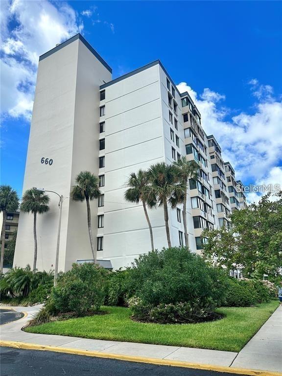 a front view of multi story residential apartment building with yard and sign board