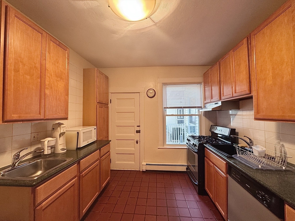 a kitchen with granite countertop a sink stove and cabinets