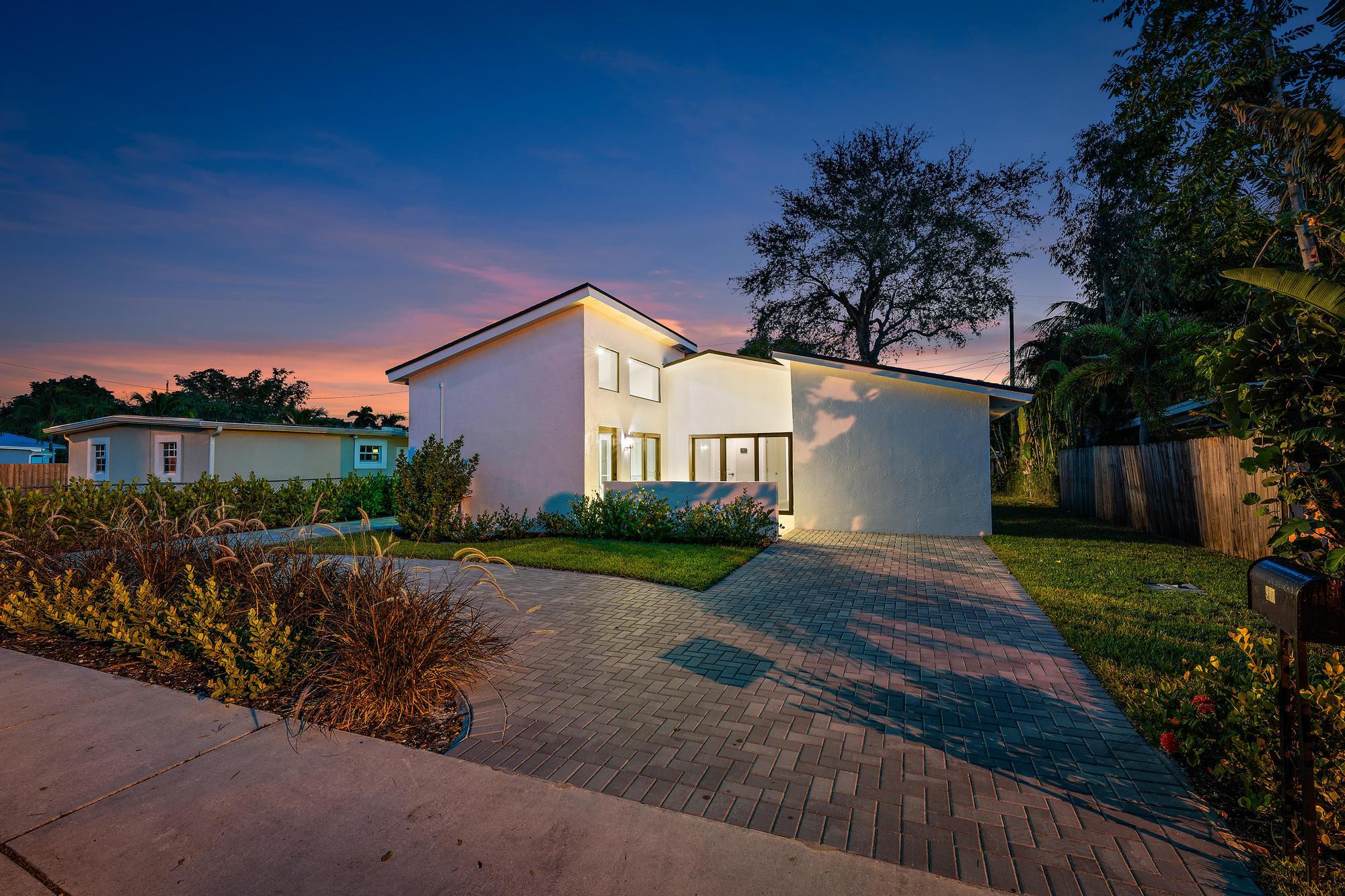 a front view of a house with a garden and trees