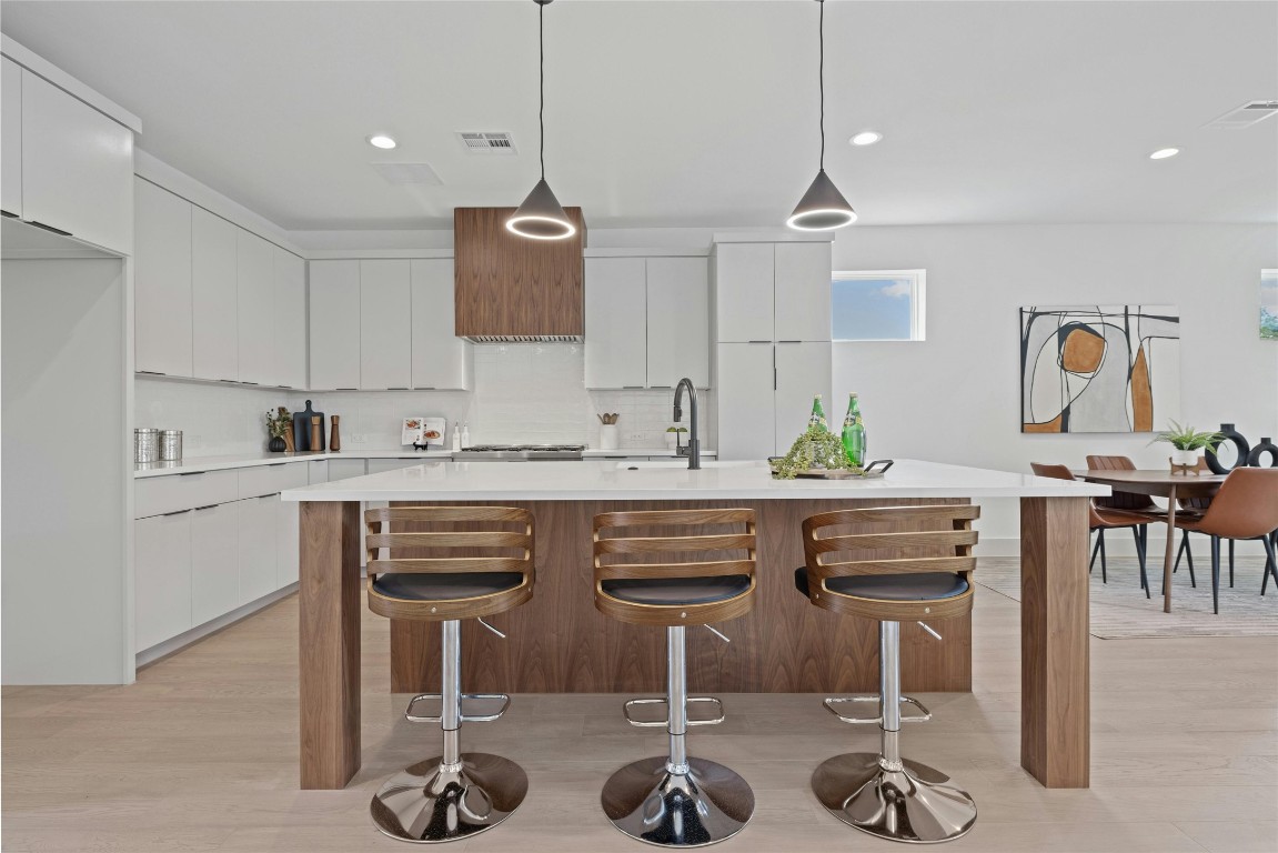 a kitchen with stainless steel appliances kitchen island granite countertop a dining table chairs and sink