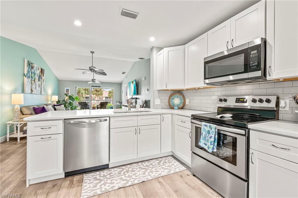 a kitchen with stainless steel appliances granite countertop a sink a stove top oven and white cabinets