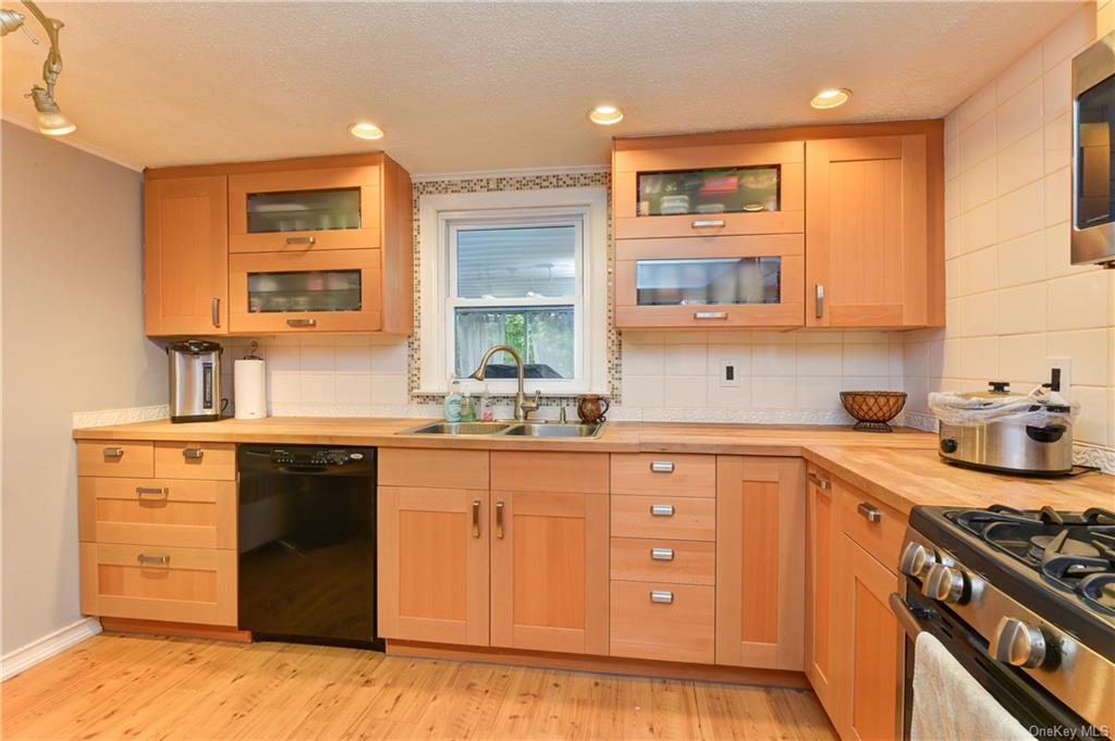 Kitchen with light hardwood / wood-style floors, sink, tasteful backsplash, and stainless steel appliances