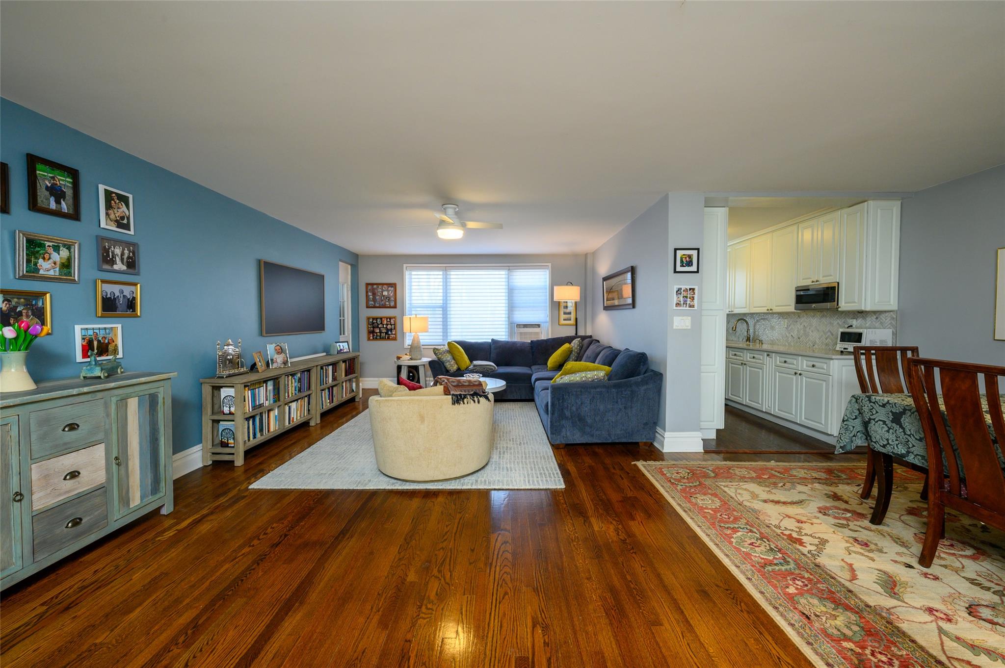 Living room with ceiling fan, sink, and dark wood-type flooring