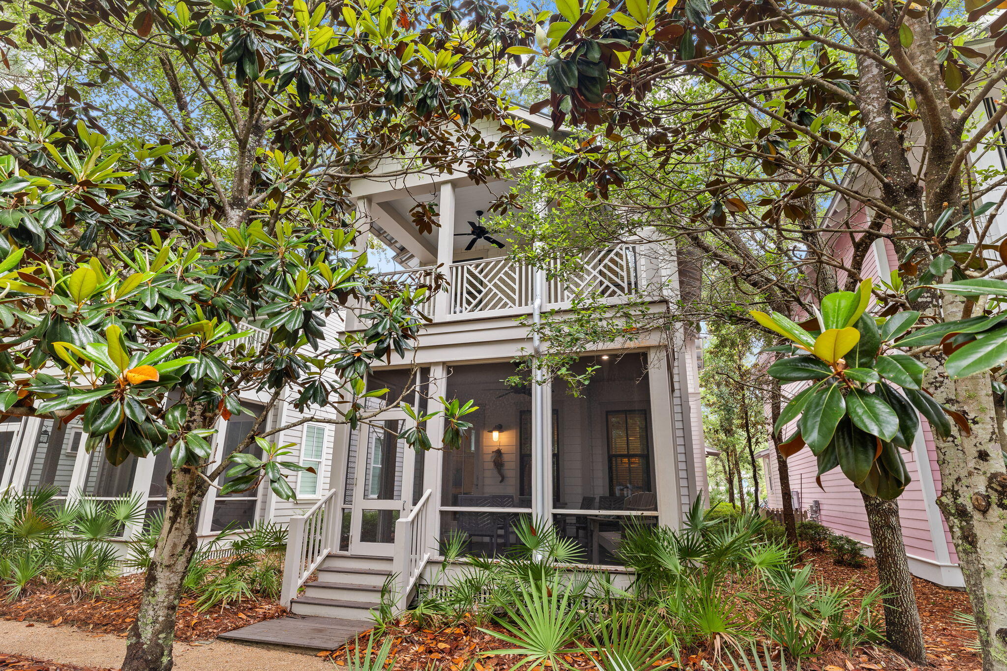 front view of a house with potted plants and large trees