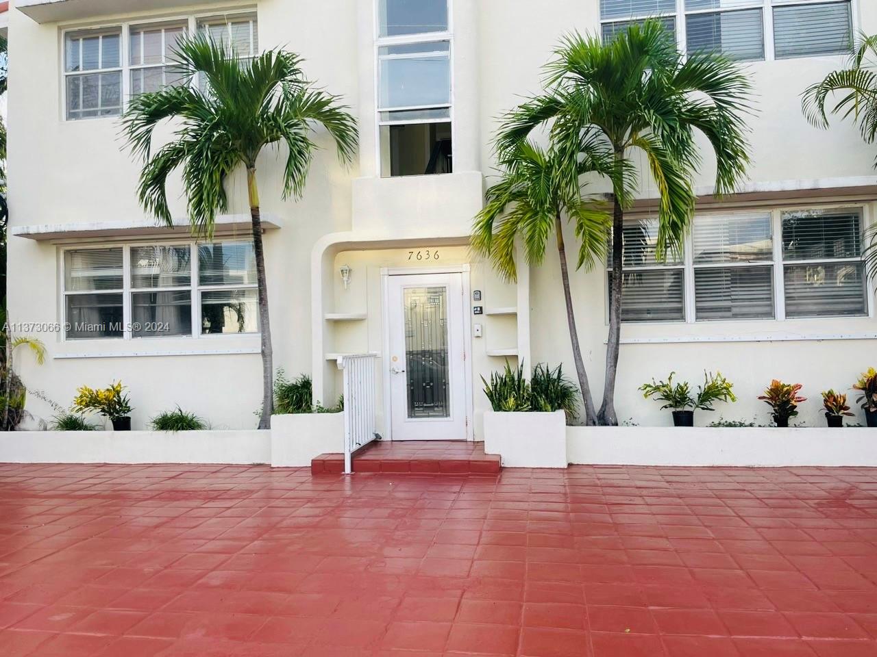 a front view of multiple houses with palm trees