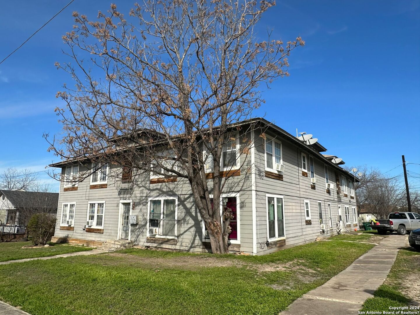 a view of a white house with a big yard and large trees