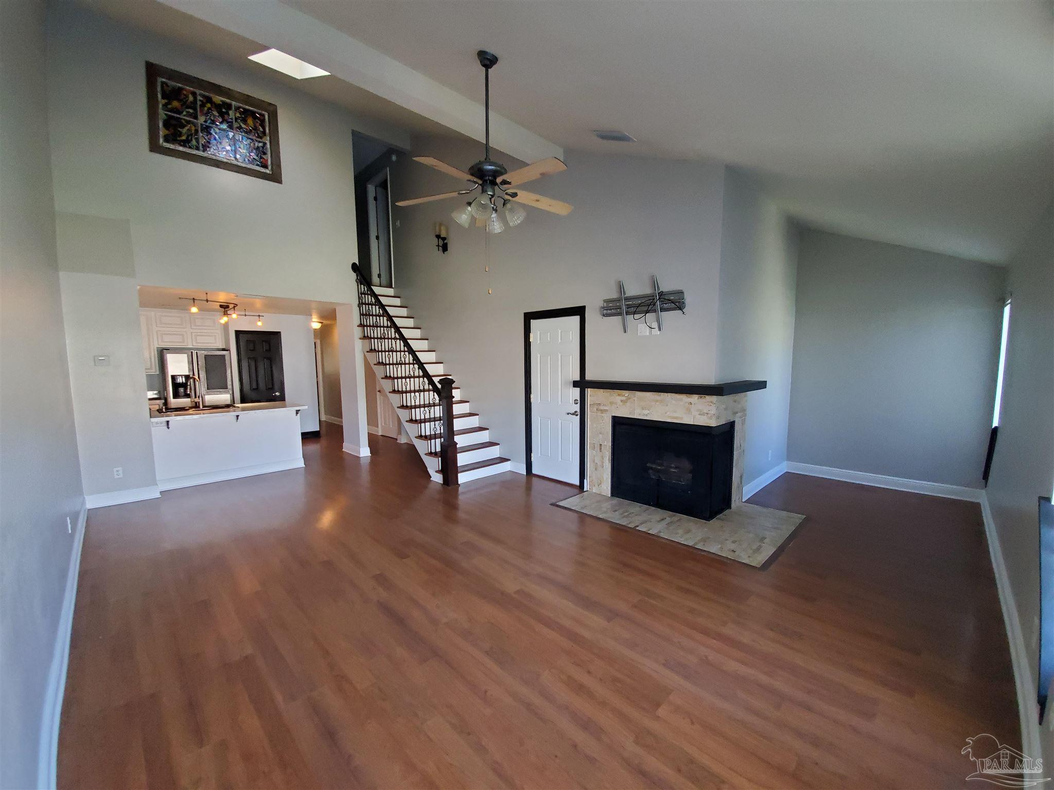 a view of a livingroom with wooden floor a fireplace and entryway