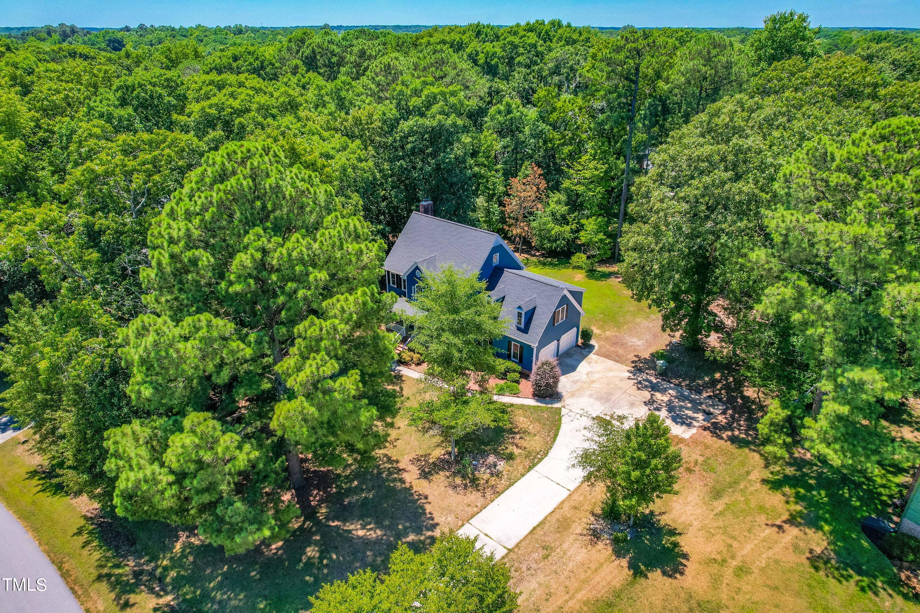 an aerial view of a house with a yard and large trees