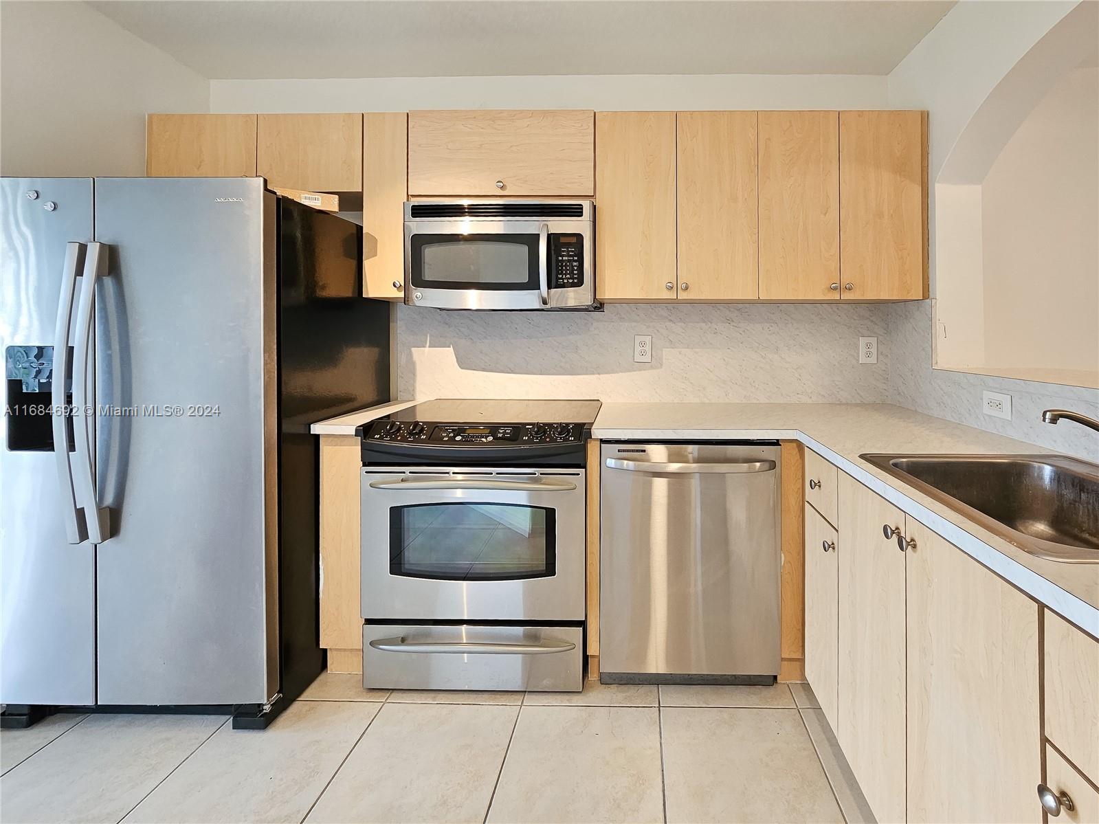 a kitchen with stainless steel appliances a refrigerator sink and microwave