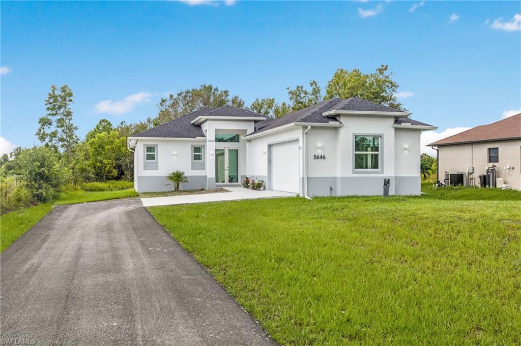 View of front of property featuring a front yard, cooling unit, and a garage