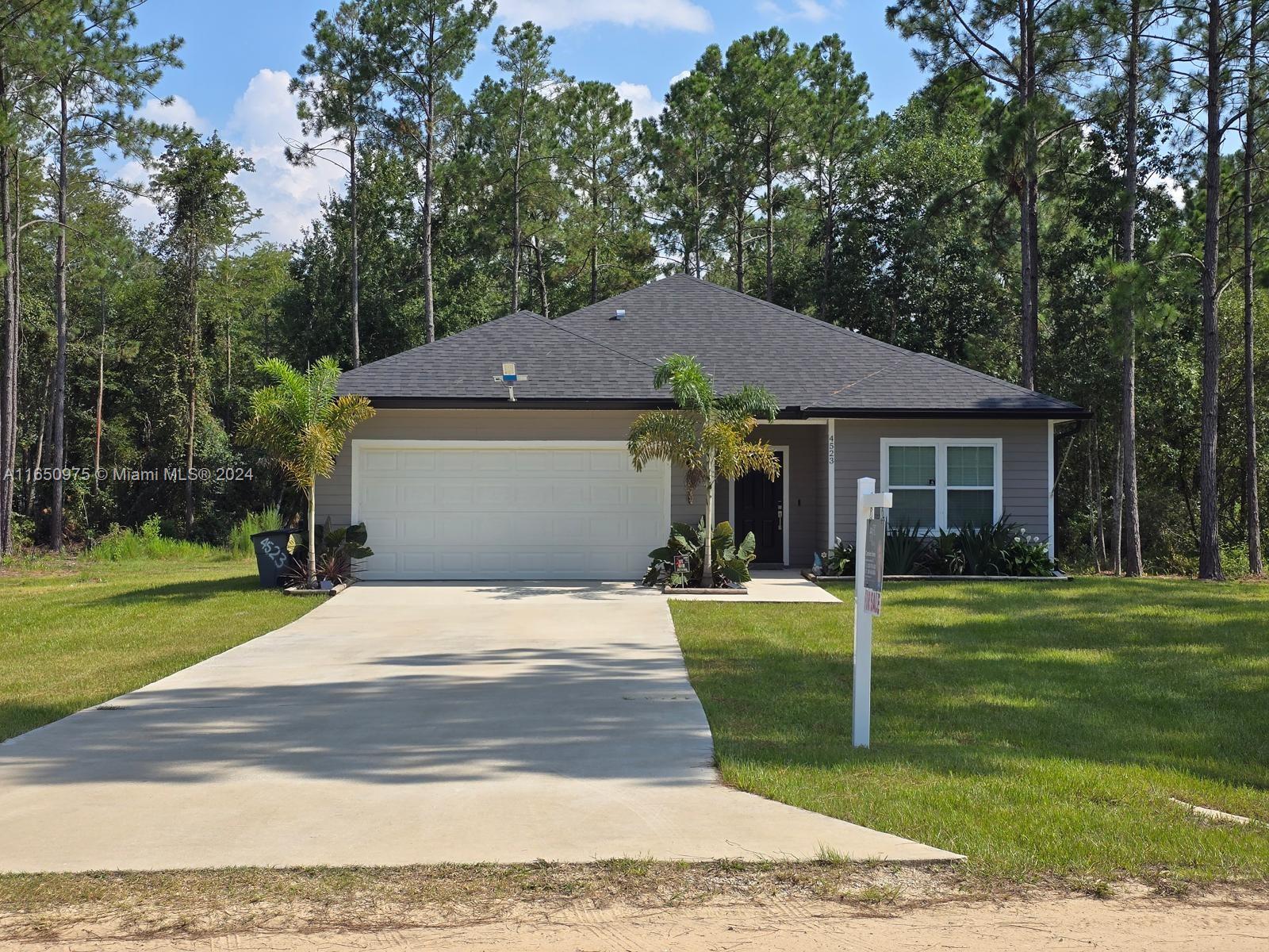 a front view of a house with a garden and trees