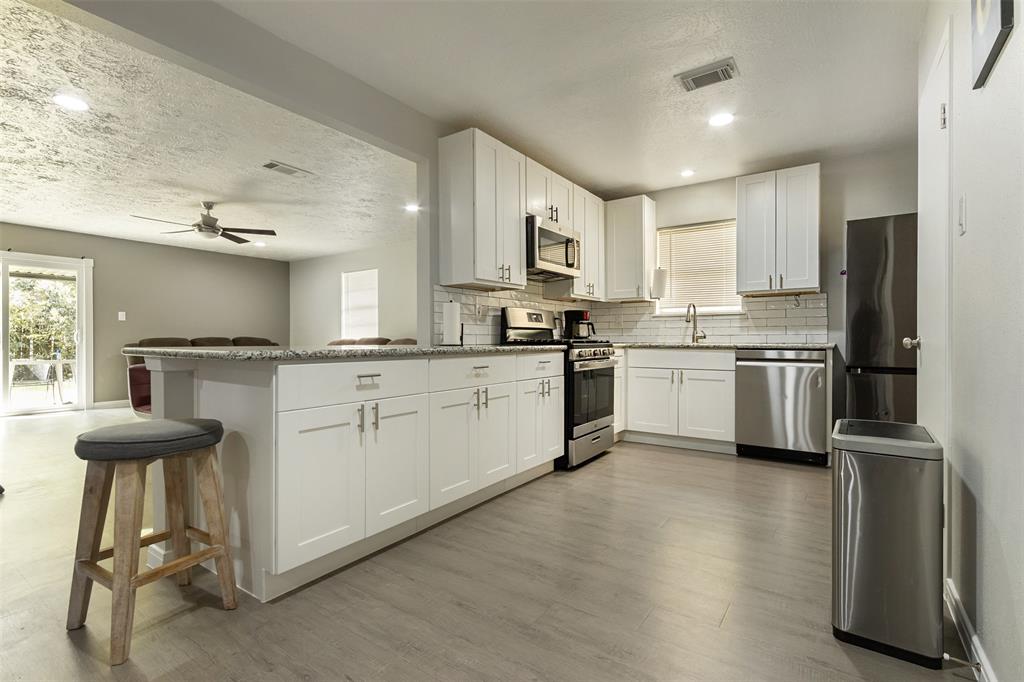 a kitchen with stainless steel appliances kitchen island granite countertop a sink cabinets and wooden floor