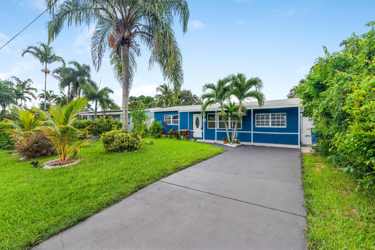 a view of a house with a yard and palm trees