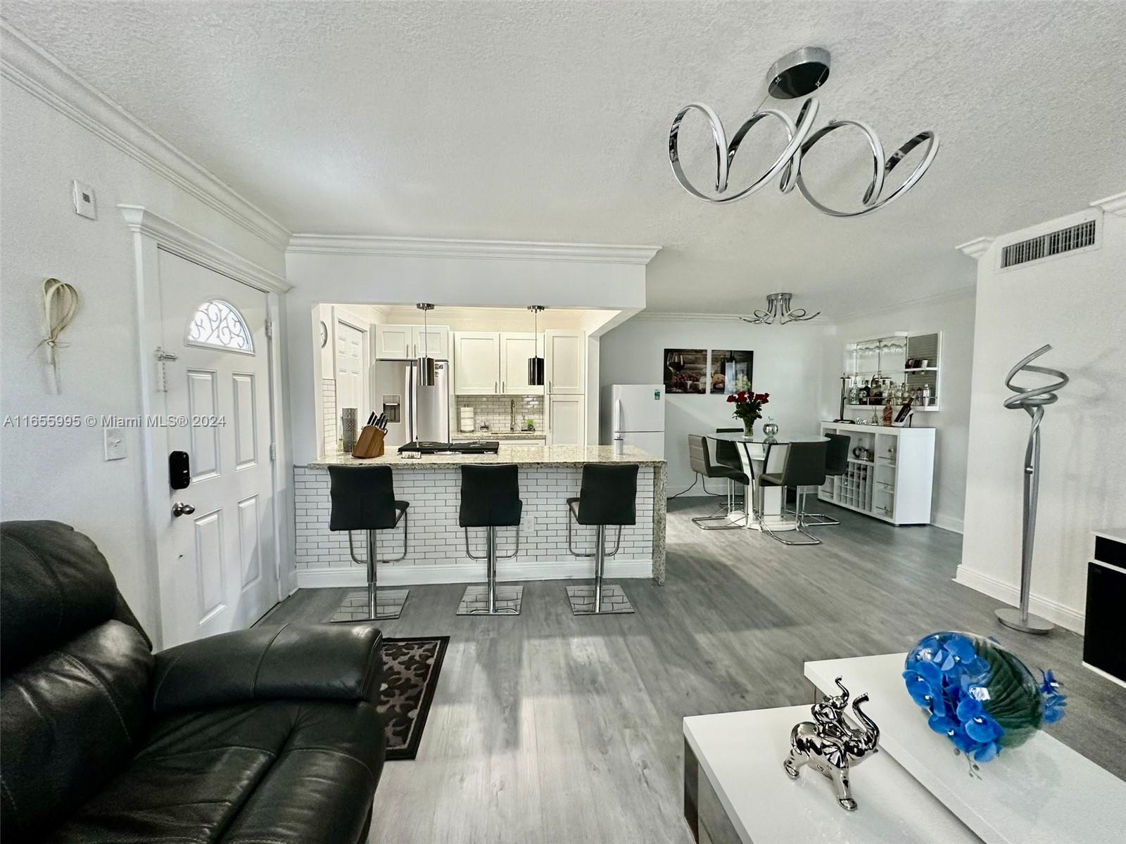 a living room with furniture kitchen view and a chandelier