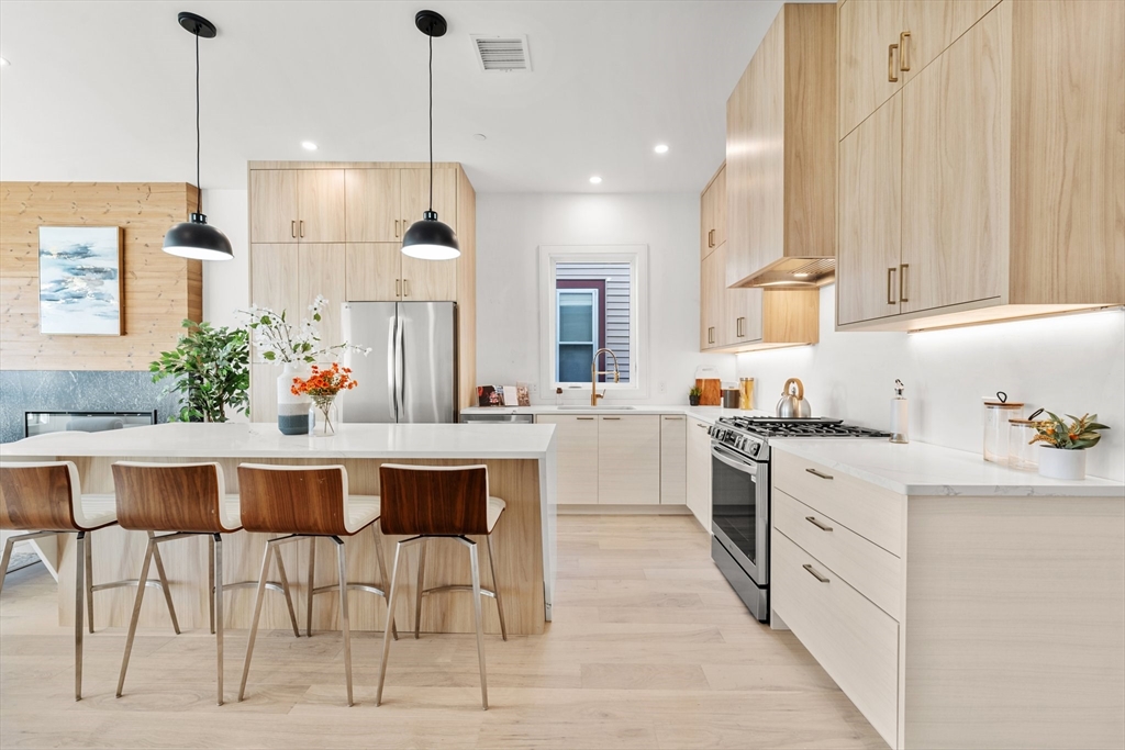 a kitchen with stainless steel appliances kitchen island granite countertop a table chairs sink and cabinets