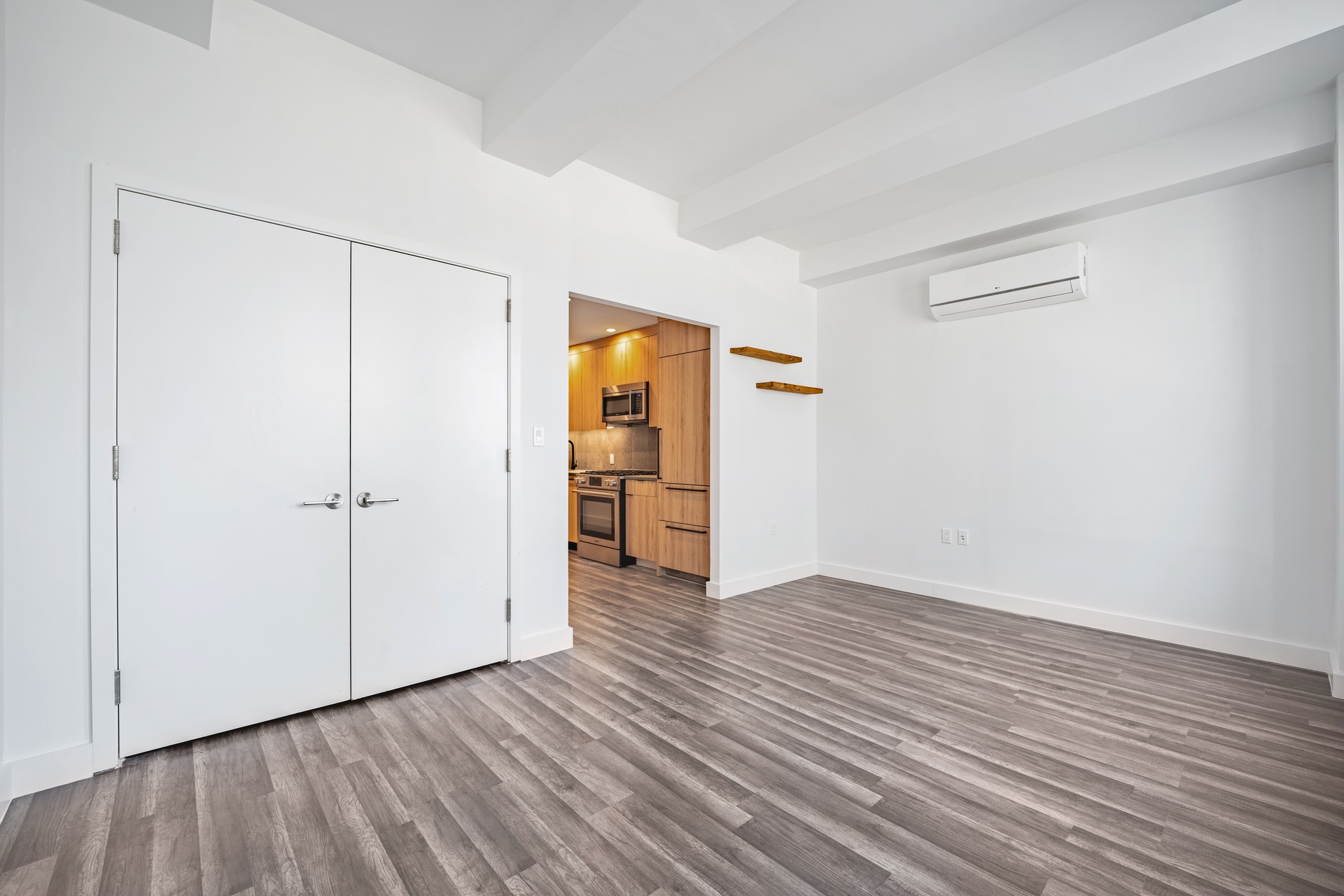 a view of an empty room with wooden floor and closet