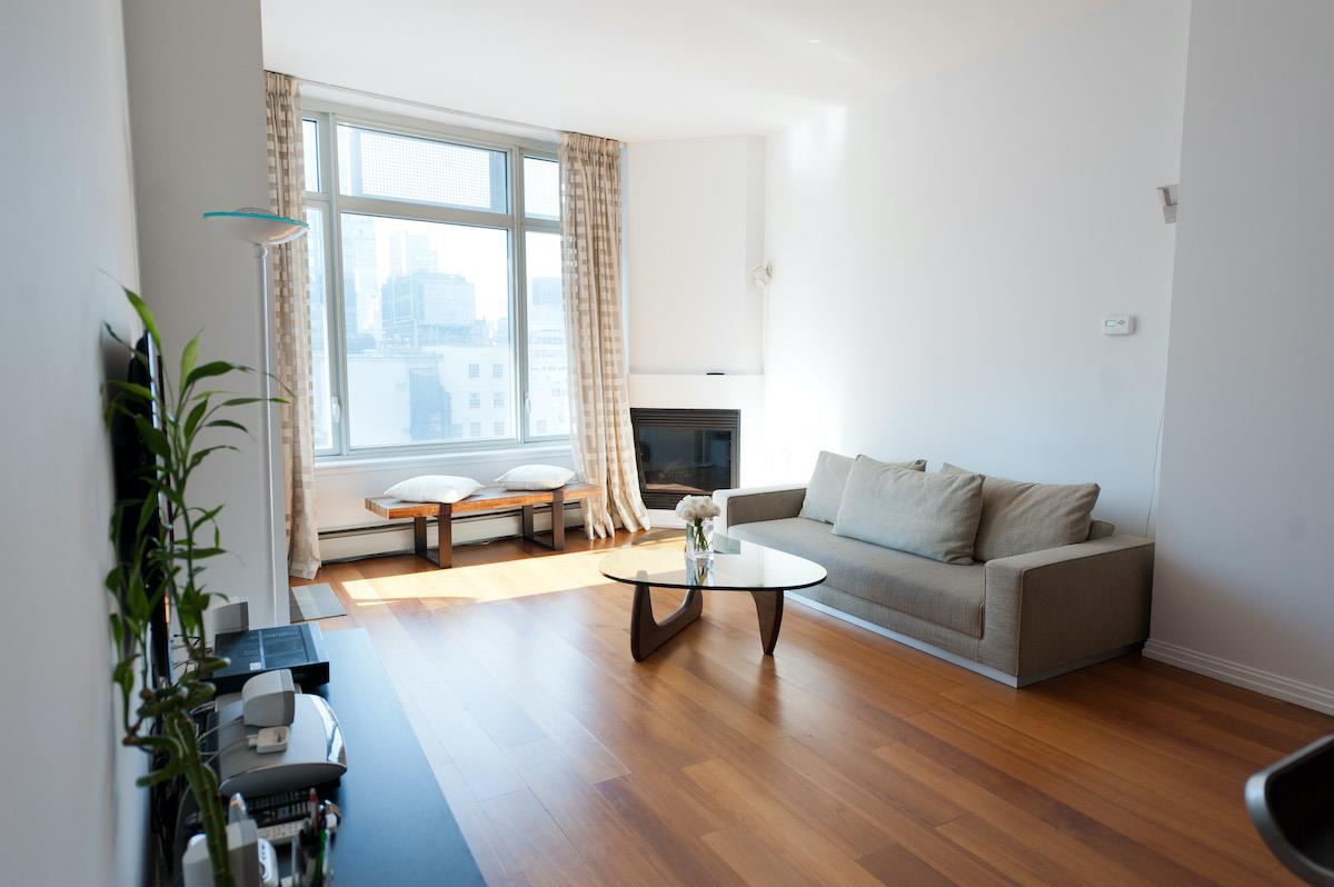 a living room with furniture large window and wooden floor