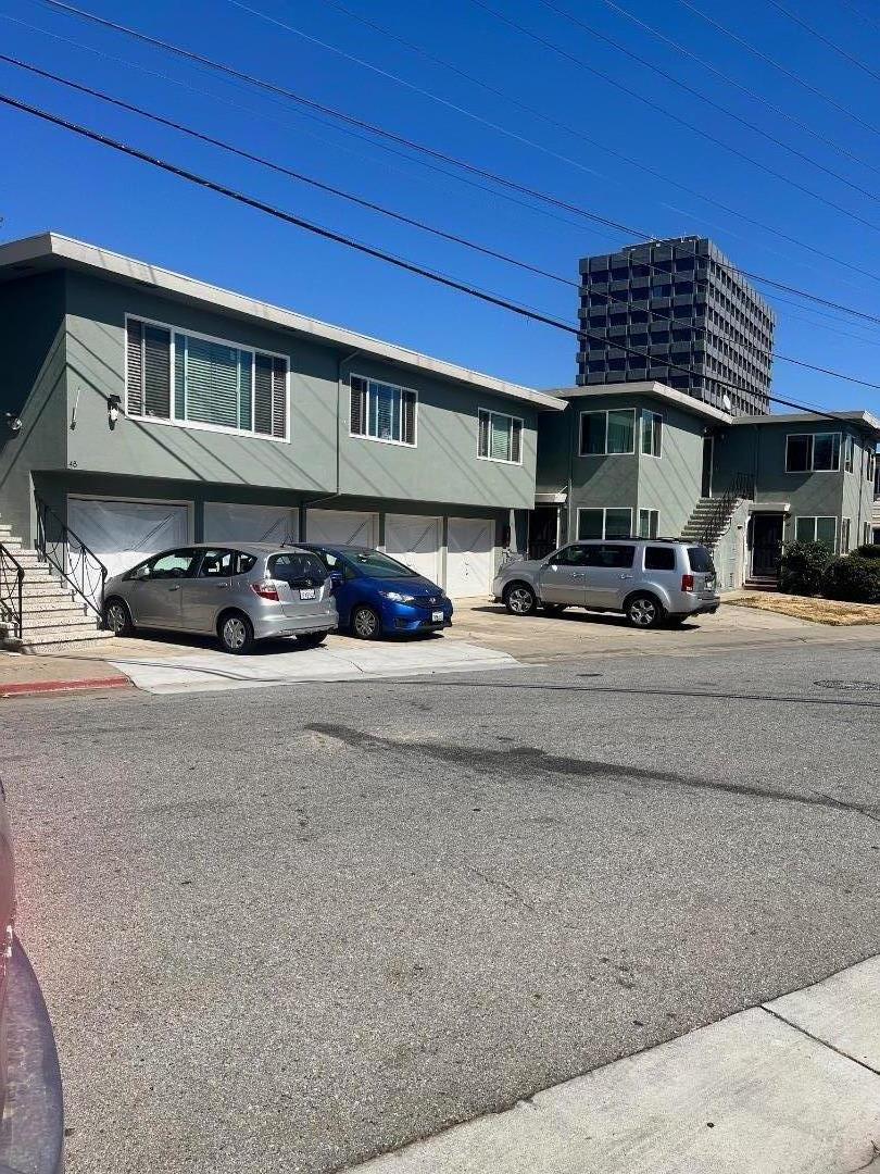 a front view of a building with cars parked