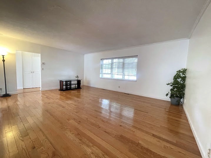 a view of empty room with wooden floor and window