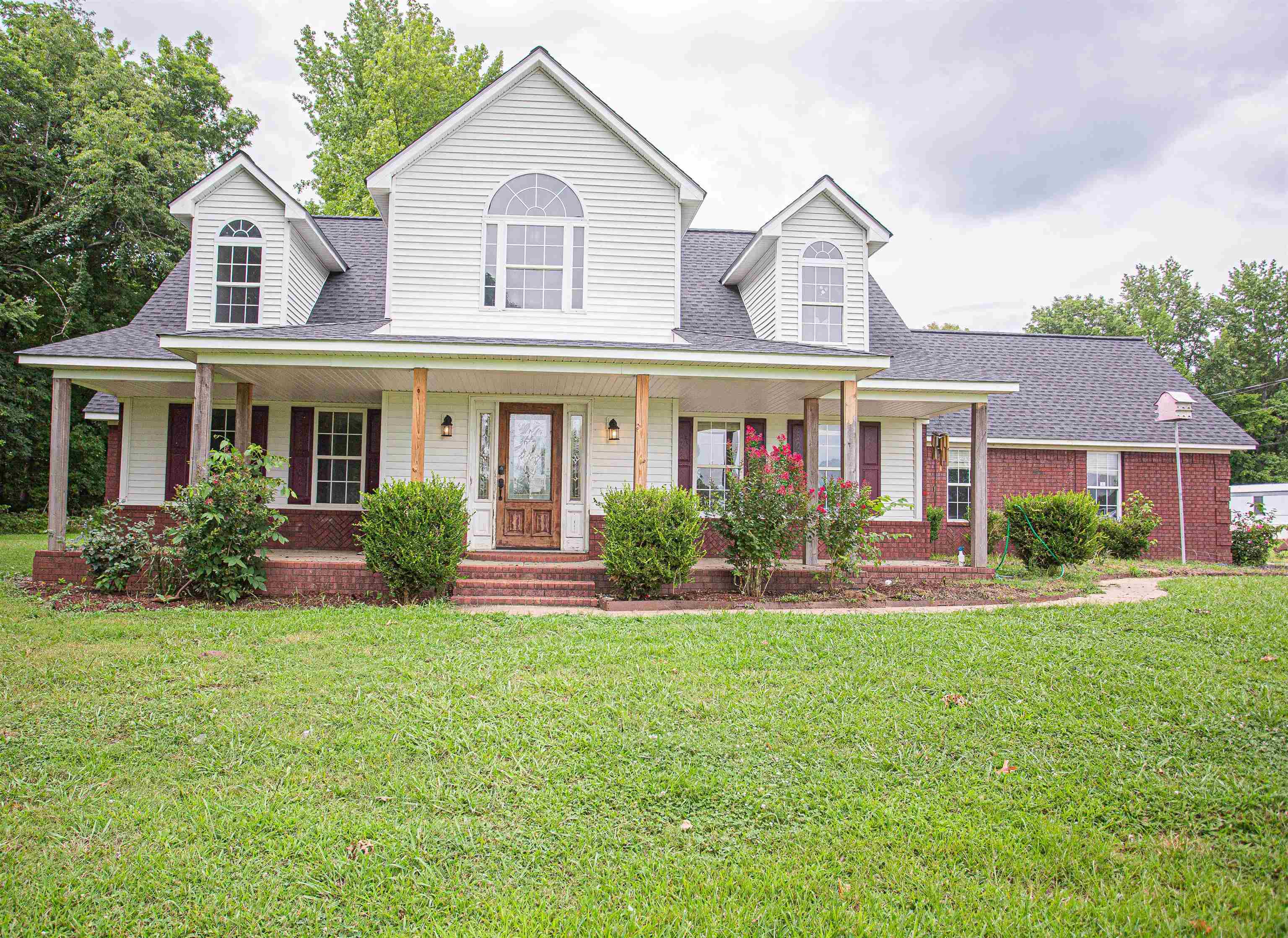 Cape cod home featuring a front yard and a porch