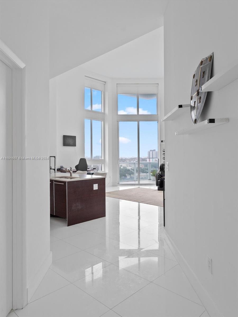 a large white room with kitchen island and a view of living room