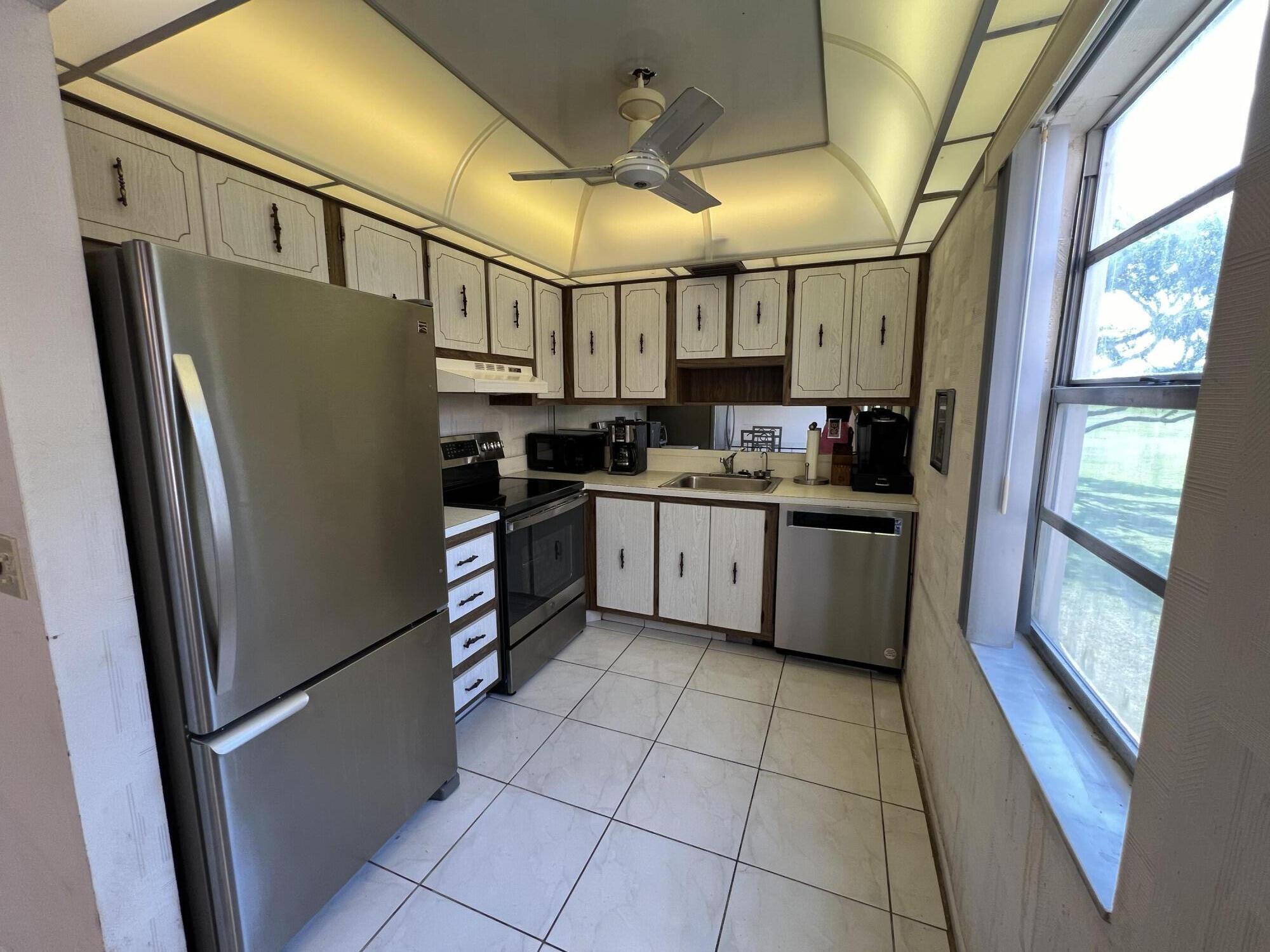 a kitchen with stainless steel appliances granite countertop a refrigerator a sink and white cabinets