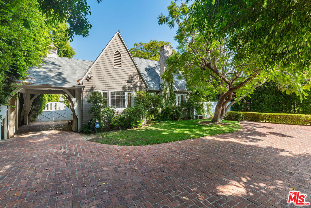 a view of a house with a yard and large trees