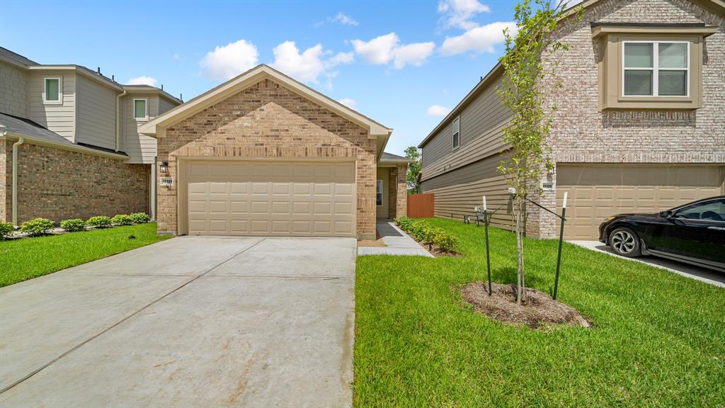 a view of a house with a small yard and a large parking space