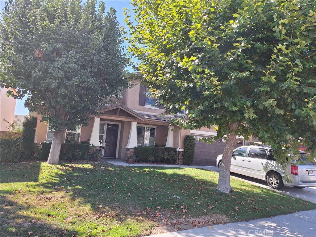 a front view of a house with a garden and tree