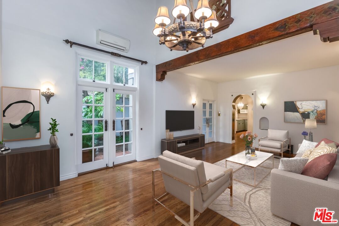 a living room with furniture a chandelier and a flat screen tv