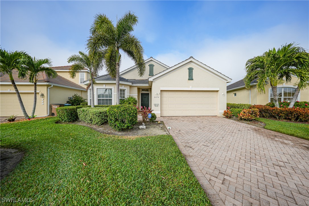 a front view of a house with a garden and palm trees