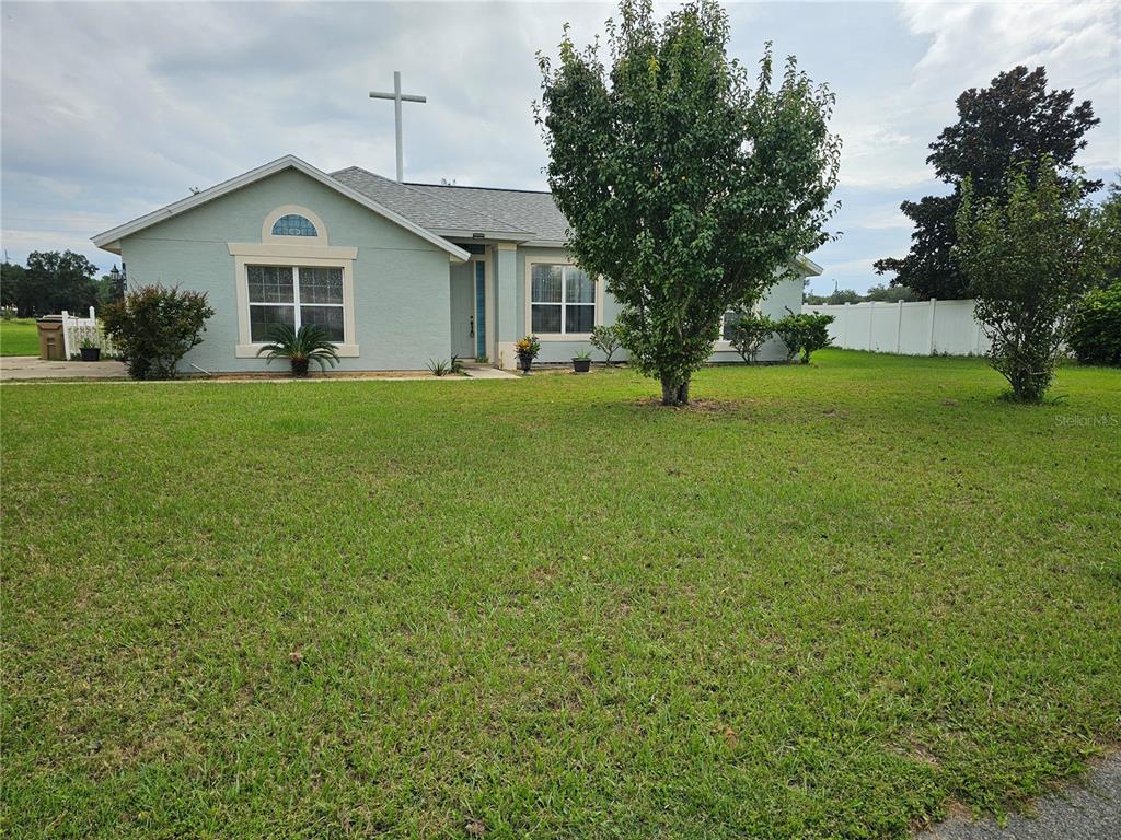 a view of a house next to a big yard and large trees