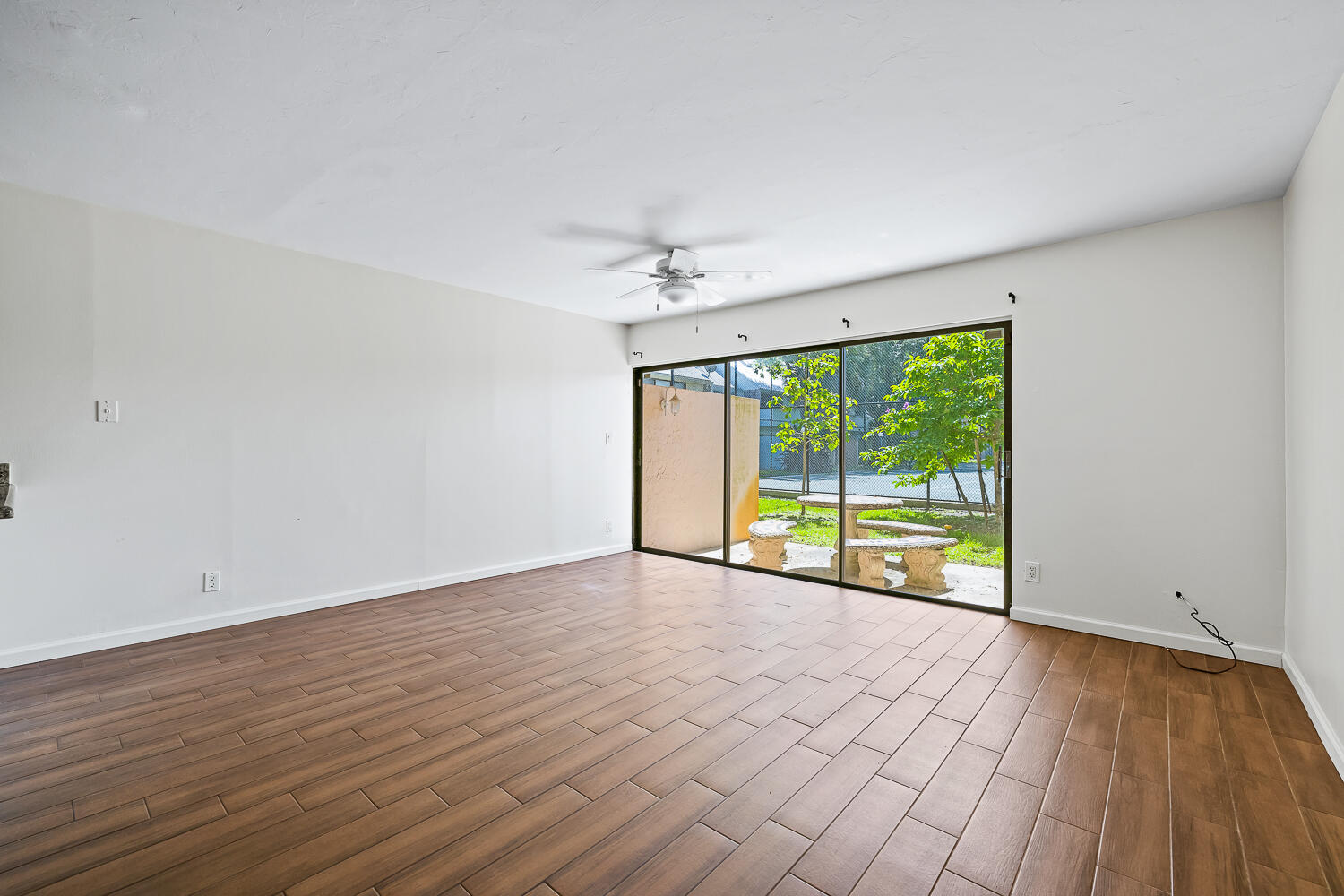 a view of an empty room with a window and wooden floor