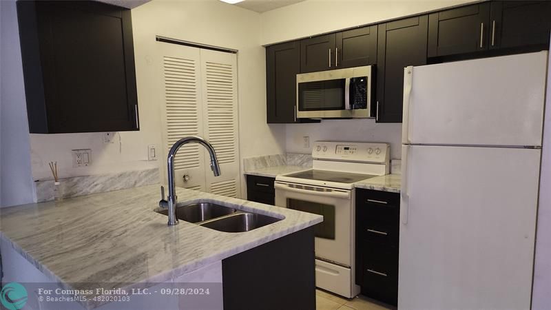 a kitchen with a sink a microwave a refrigerator and cabinets