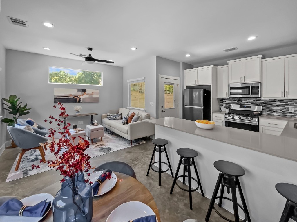 a living room with furniture kitchen view and a large window