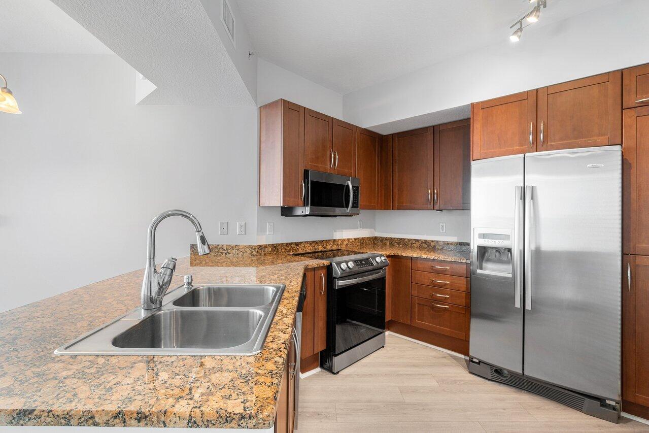 a kitchen with granite countertop a refrigerator and a sink