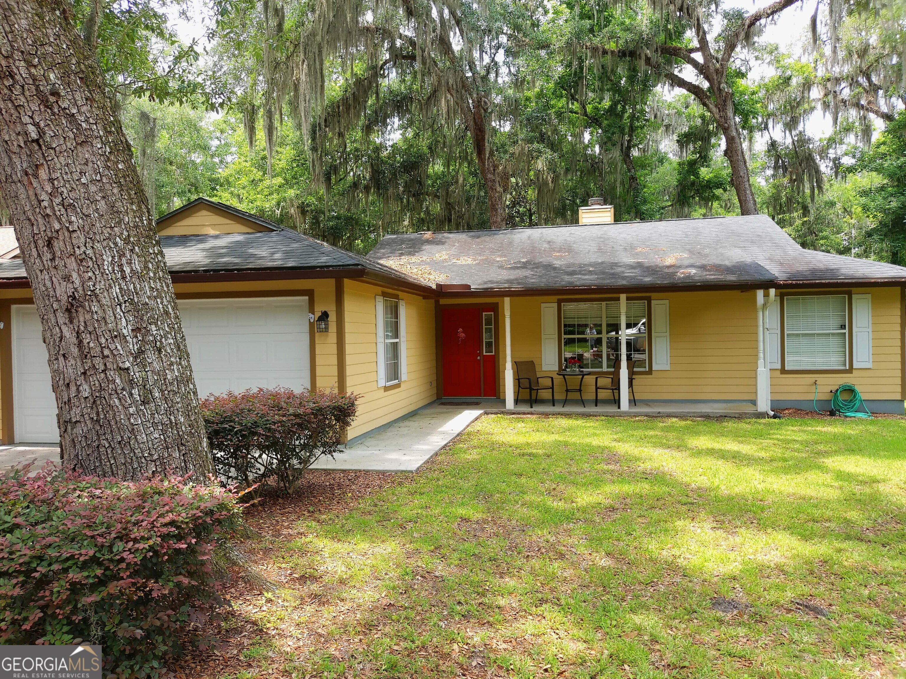 a front view of a house with a garden and trees