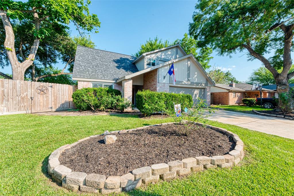 a view of a house with a yard potted plants and a large tree