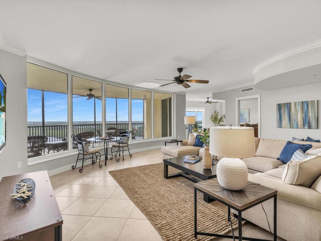 Tiled living room with a wall of windows, crown molding, and a healthy amount of sunlight