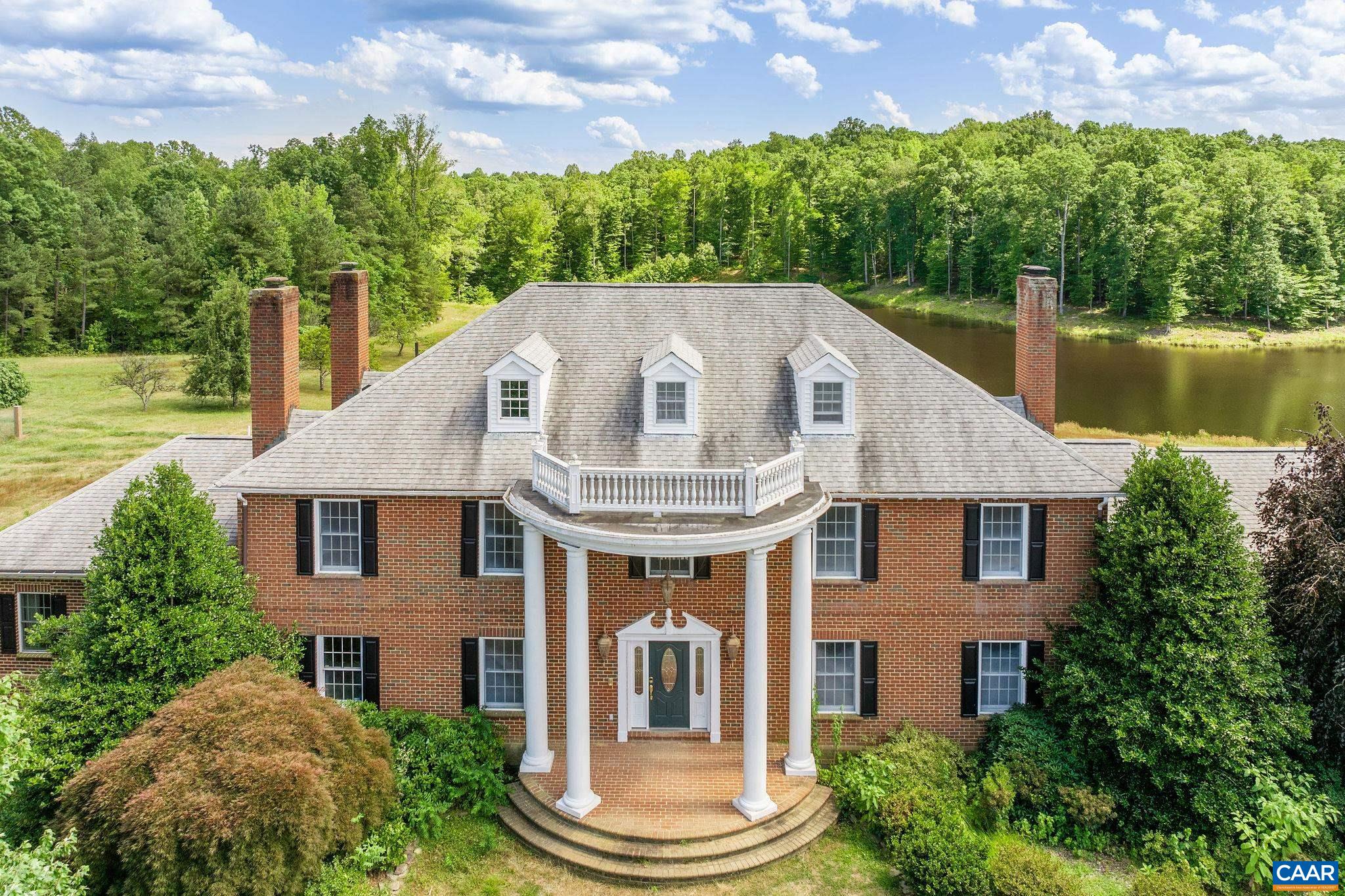 a front view of a house with a garden and lake view