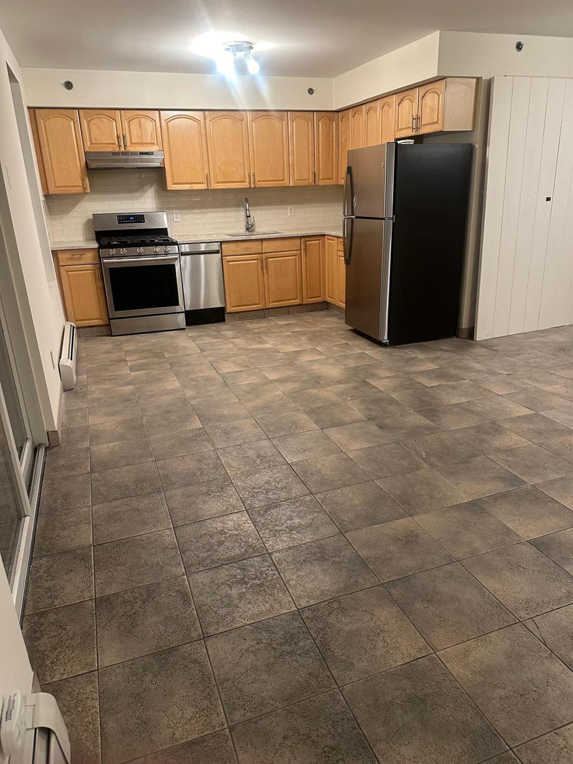 Kitchen with light brown cabinets, sink, stainless steel appliances, and tasteful backsplash